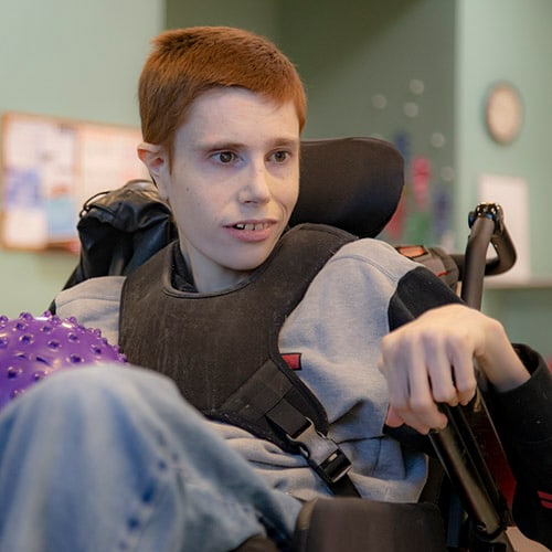 Persona sitting in a wheelchair while receiving care at a local program for adults with disabilities.