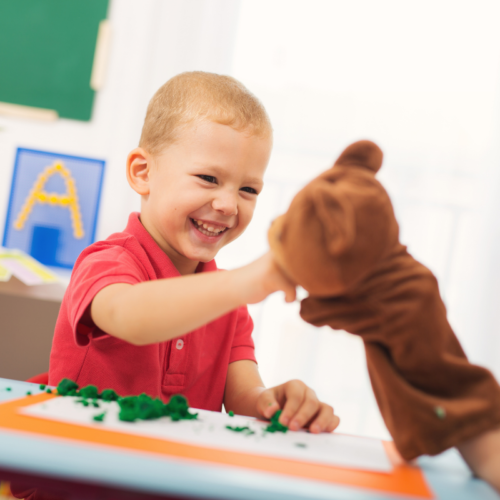 ABAstockimage Child smiling and playing with bear puppet.