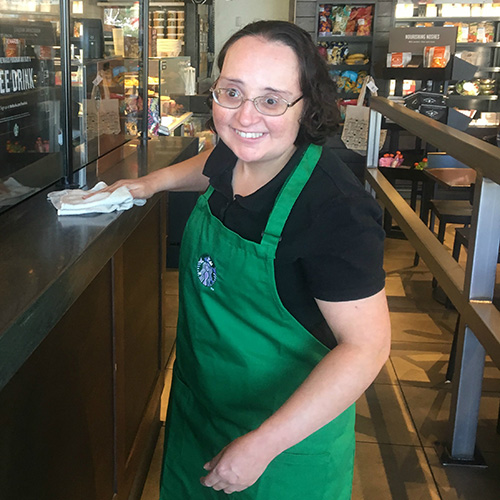 Person wiping down counter at a coffee shop.