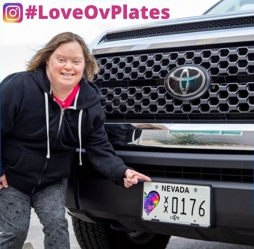 Woman pointing to a Nevada charity license plate on a black truck.