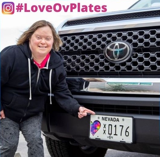 charity-license-plate-nevada Woman pointing to a Nevada charity license plate on a black truck.