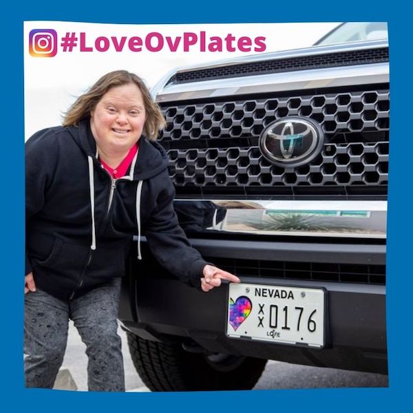 charity-license-plate-nevada Woman pointing to a Nevada charity license plate on a black truck.