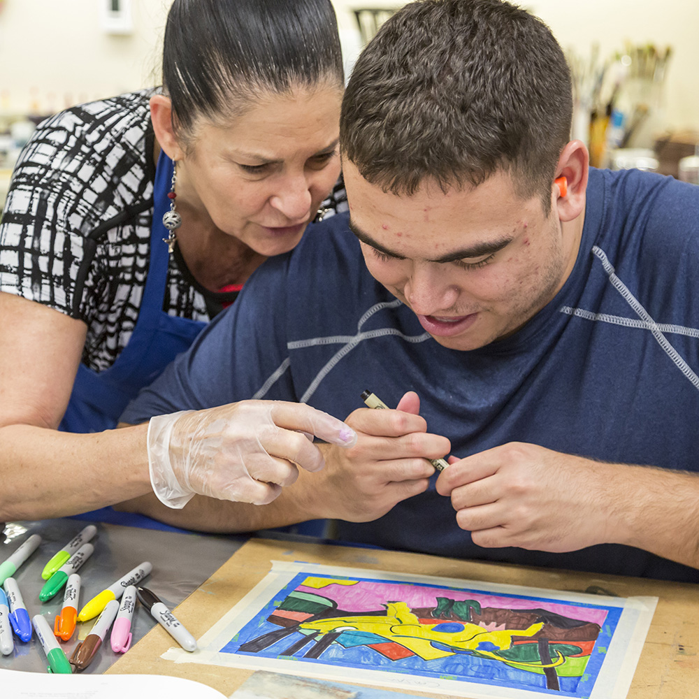 An instructor helps a man with an intellectual disability in the Fine Art Program run by the nonprofit Opportunity Village.