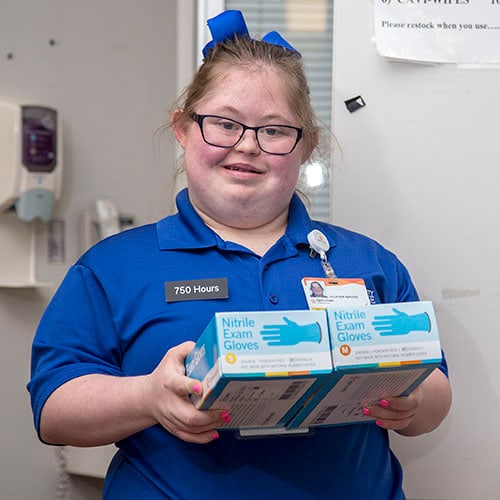 Young woman holding glove boxes while at work.