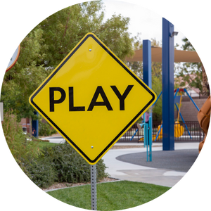 Yellow street sign displaying the word "play" at an accessible playground.