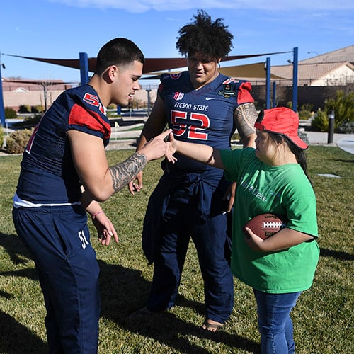 Three people standing on a football field.