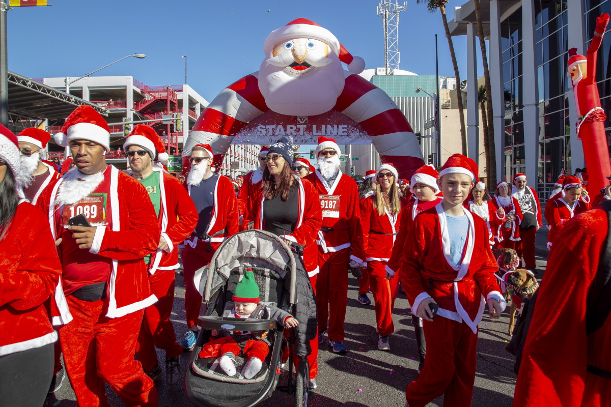 Group of people dressed in Santa Claus costumes in the street.
