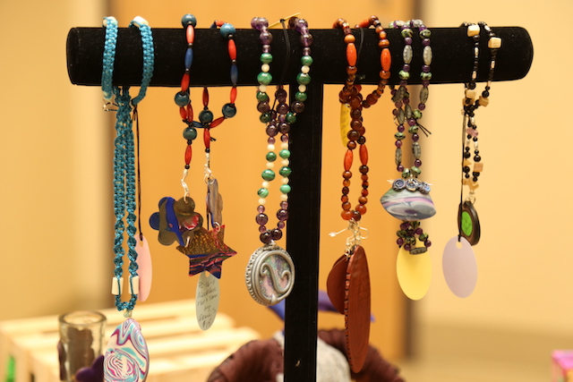 Handmade clay jewelry on a stand.