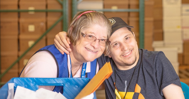 Woman and man leaning their heads together and smiling while working together.