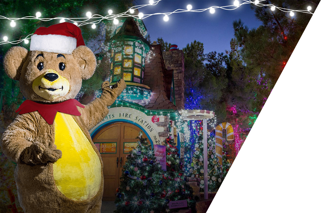 Large bear costume with Santa hat standing in front of Magical Forest in Las Vegas.