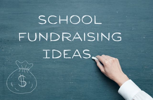 person writing 'school fundraising ideas' on a chalkboard