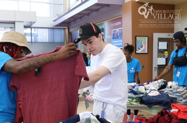 people sorting through clothes at a community center rummage sale