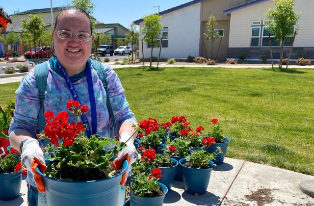 Person standing with a flower pot in her hands.