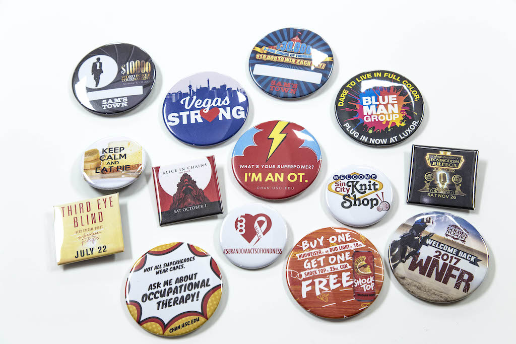 Variety of promotional button and pin examples on a white background.