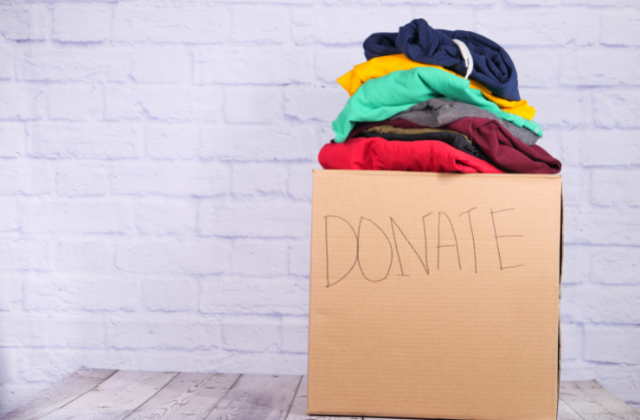 Cardboard box filled with clothing for donation.