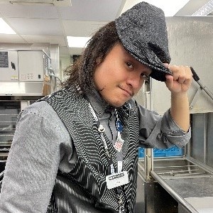 Young man with hat standing in a commercial kitchen.