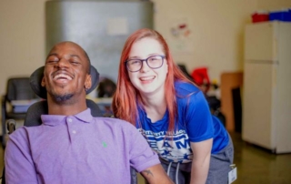 Woman crouching down by man in a wheelchair.