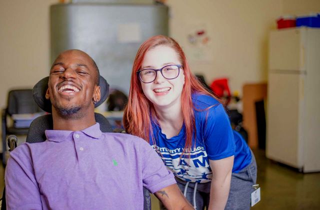 Woman crouching down by man in a wheelchair.