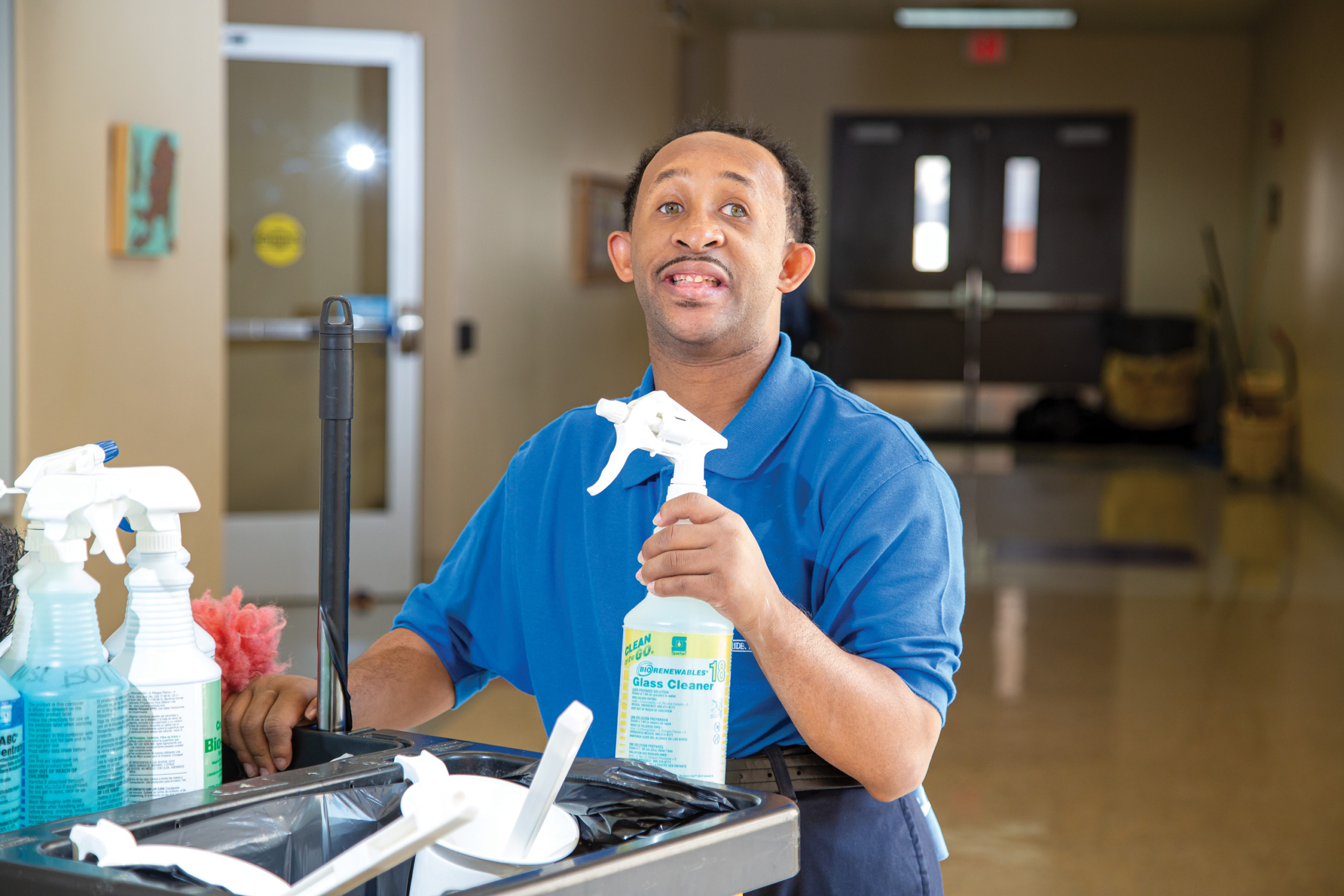 Custodian holding a bottle of glass cleaner.