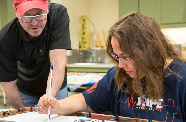 Man helping an adult woman with an art project at a day program.