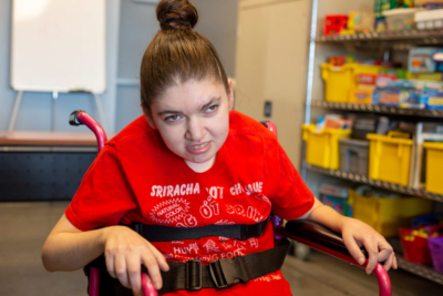 Woman in red shirt sitting in a wheelchair at a day habilitation program.