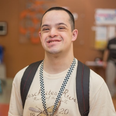 Young man wearing a white shirt and black backpack.