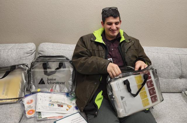 Man sitting on a coach holding a bag with documents sitting next to him.