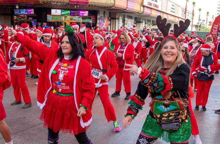 A large group of people in front of a casino dancing in Santa costumes.