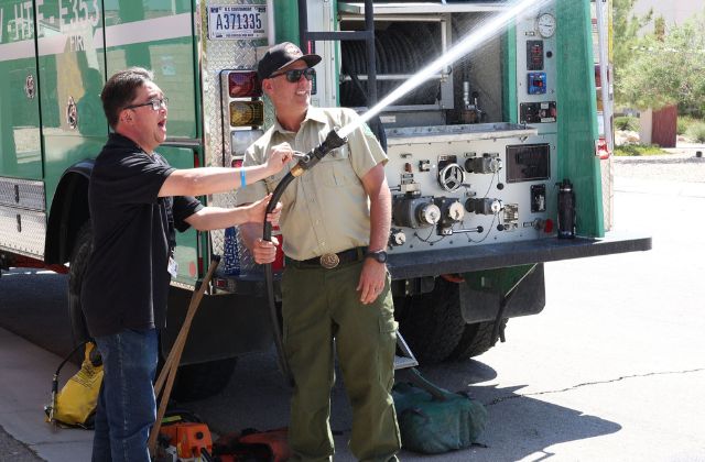 Firefighter assisted a man using a fire hose to spray water.