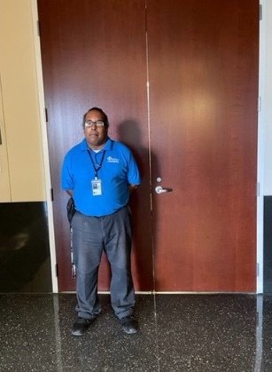 Man in a blue shirt standing in front of a large doorway.