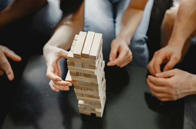 adults playing a stacking block game on a table.