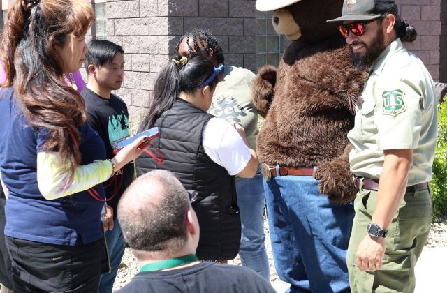 Group of people with a forest ranger and person dressed in a bear costume.