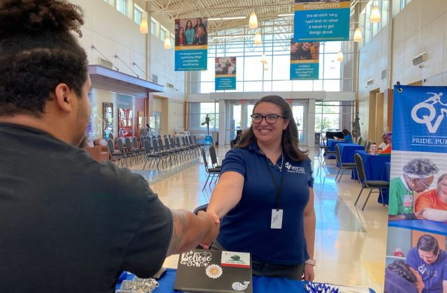 Woman at a job fair shaking the hand of an applicant.