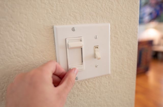 person's hand moving a light switch with a dimmer toggle