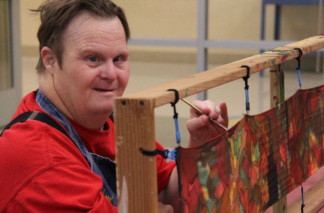 person painting a silk scarf