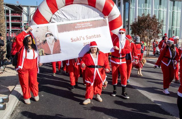 people dressed in santa suits standing in front of a fundraiser sign