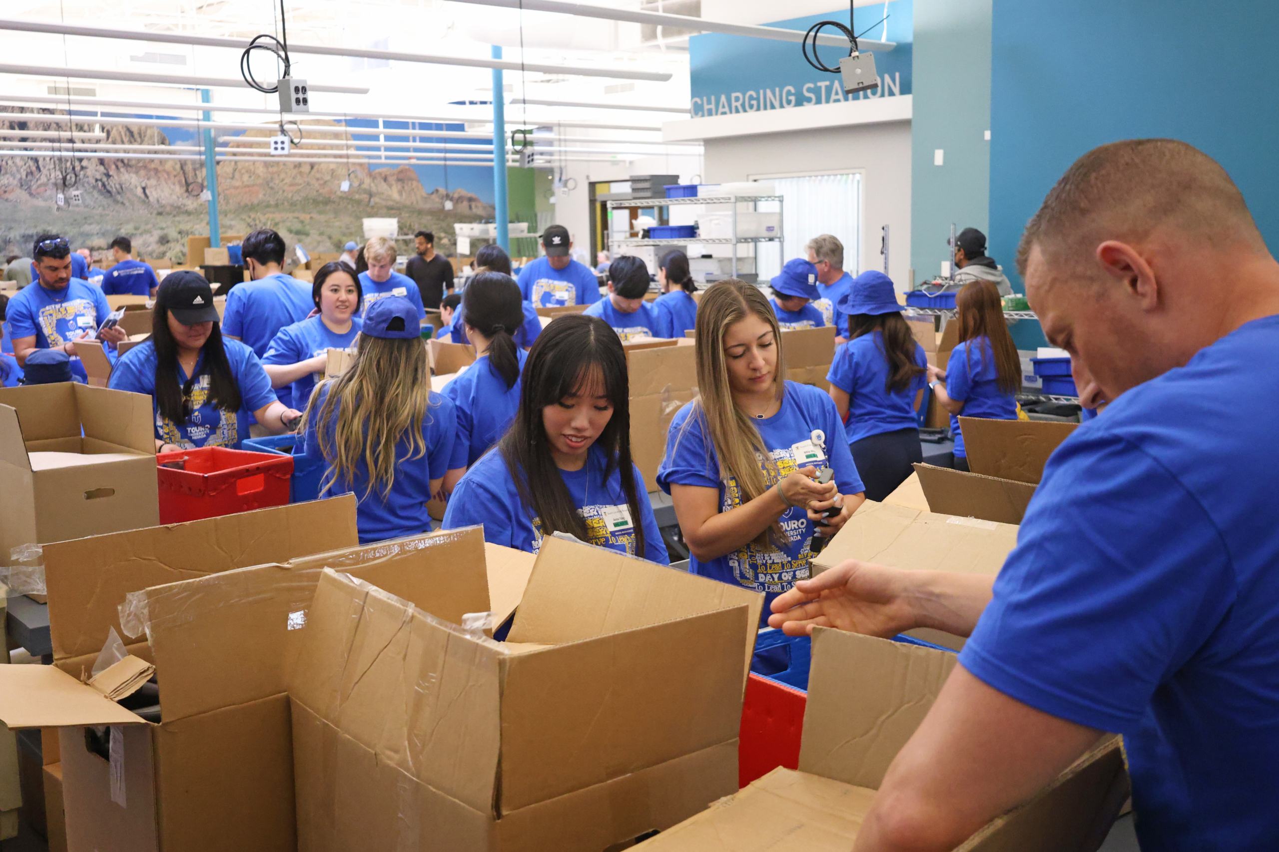 group of people in blue shirts packing cardboard boxes