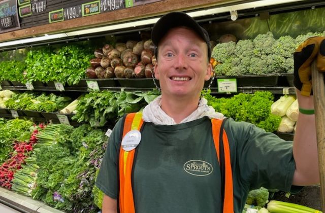 person standing in front of a produce section at a grocery store