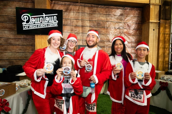group of people in santa costumes holding cookies at a fundraiser