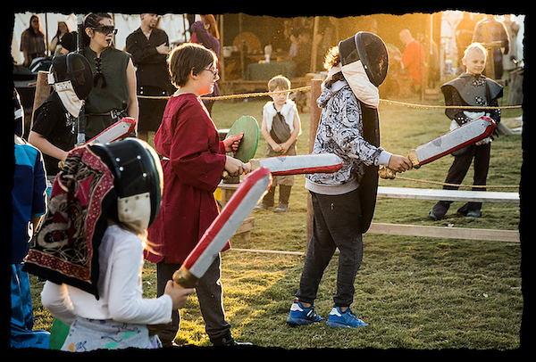 children at a renaissance fair with fake paper swords