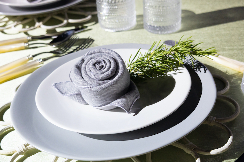 napkin rolled into the shape of a rose on a set of fine dinnerware